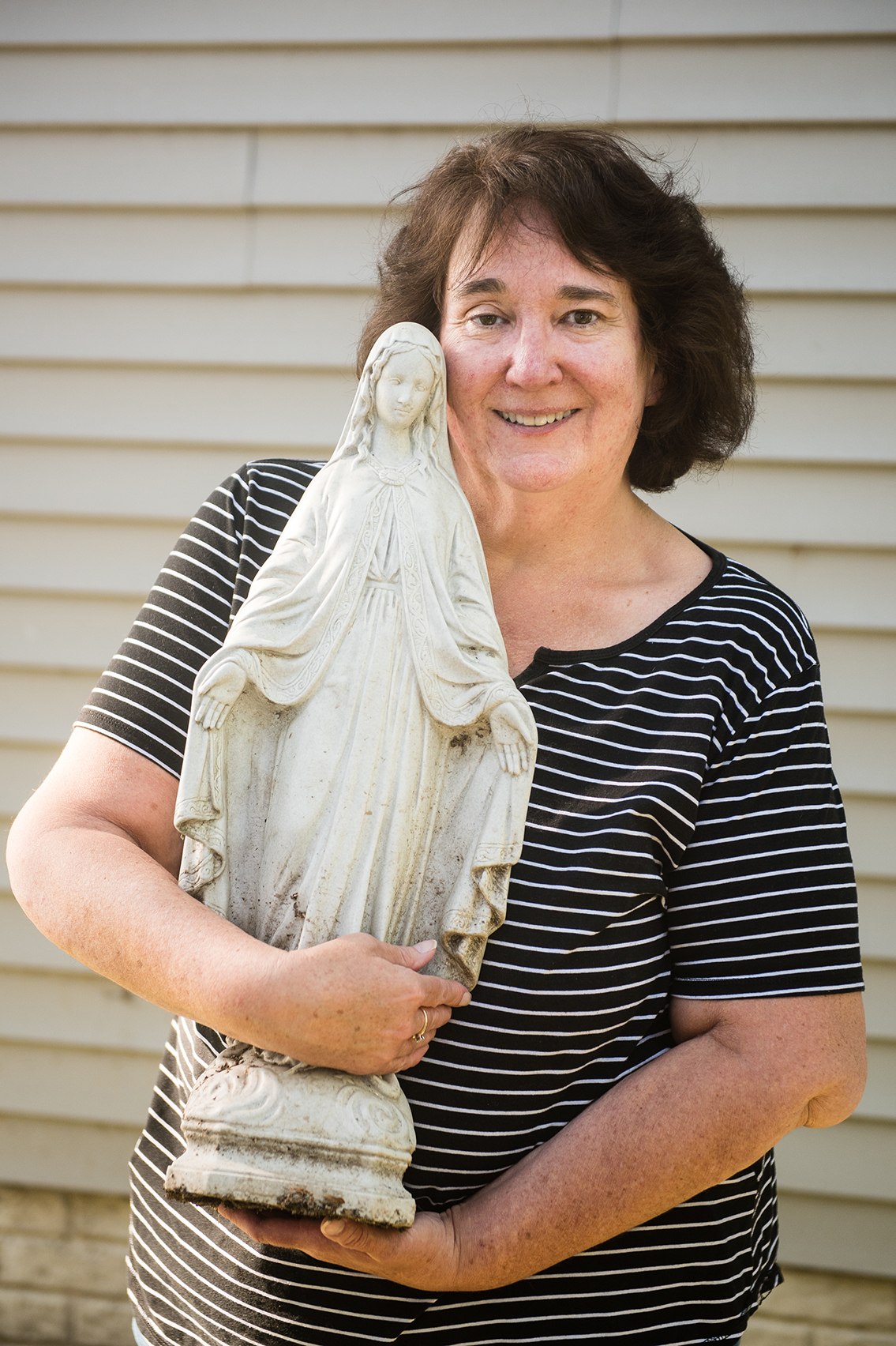 Patricia Benner holds a yard statue of Mary.