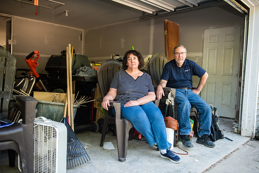 Chris and Patricia Benner sit in their garage, filled with cleanup items.