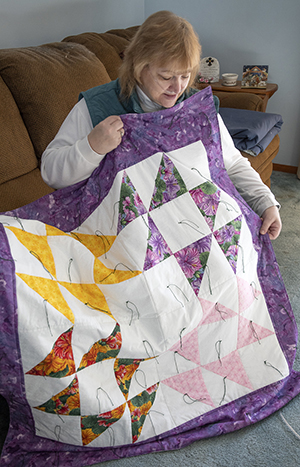 COVID-19 survivor Tammy Heinlein looks at a prayer quilt at her home in Reese. The quilt was made for her while she was in the hospital last year.