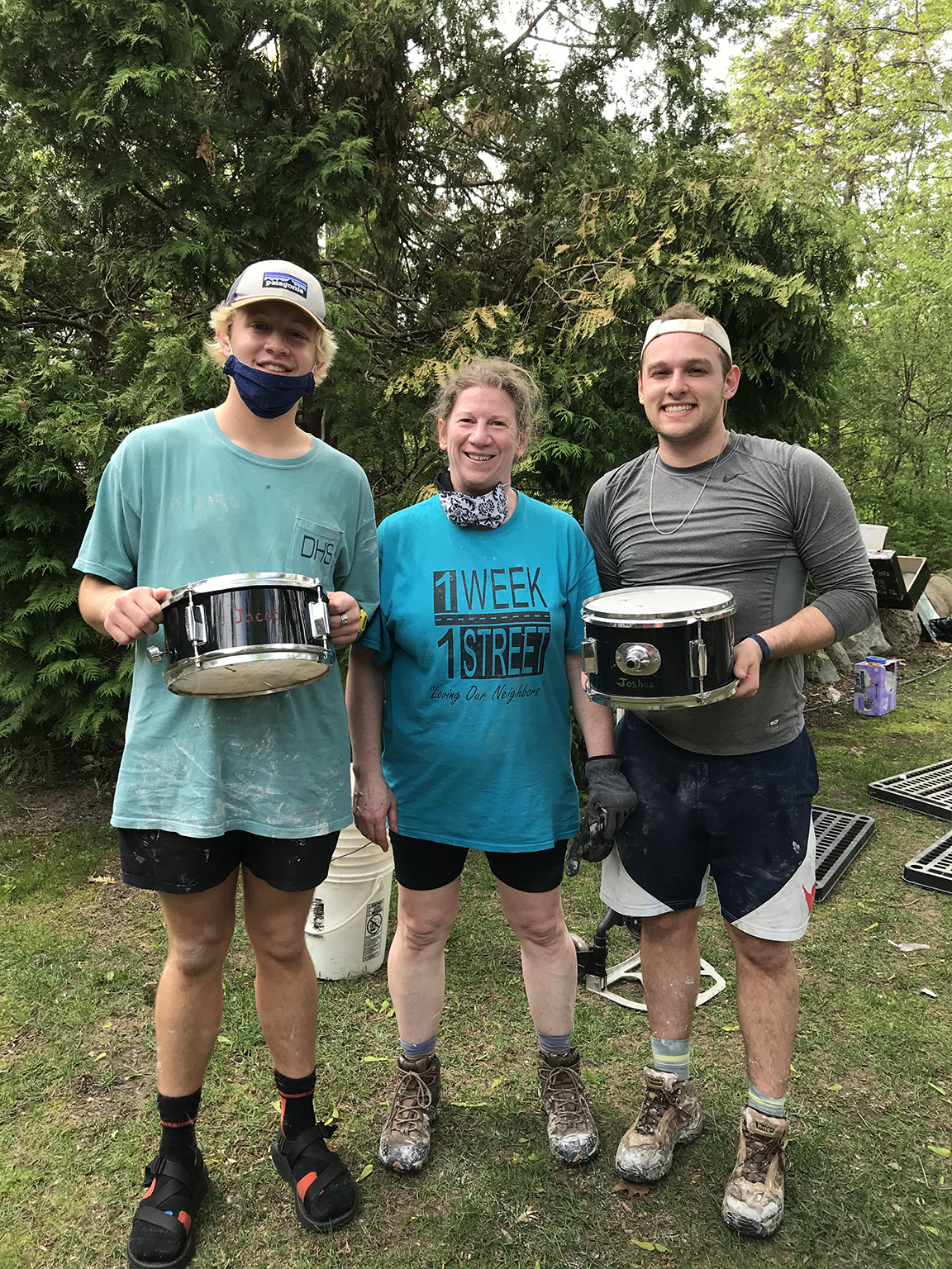 Three people hold drums after gutting a basement.