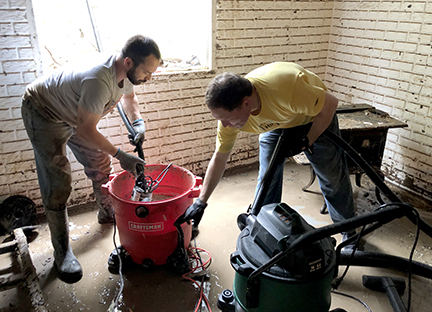 Volunteers clean water out of a basement