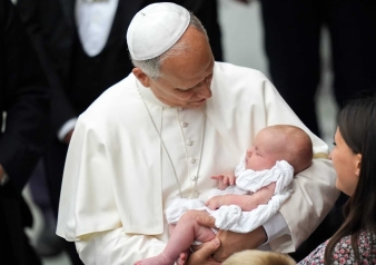 Pope Leo XIV holds a baby as he greets people in the Paul VI Audience Hall at the conclusion of his weekly general audience at the Vatican Aug. 20, 2025.