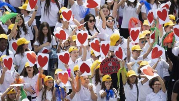Pilgrims holding drawings of a heart and a sign for the Sacred Heart Institute of Cadoneghe, Italy, join Pope Francis for the recitation of the "Regina Coeli" prayer April 23, 2023, in St. Peter's Square at the Vatican.