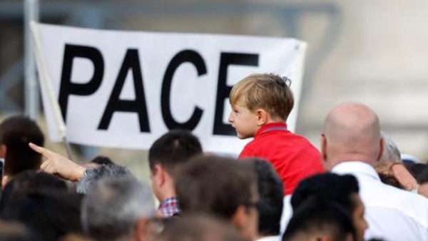 A child is near a sign that says "Pace," peace in Italian