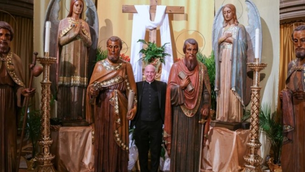 Father J.J. Mech, rector of the Cathedral of the Most Blessed Sacrament in Detroit, stands next to the life-sized statues of the apostles