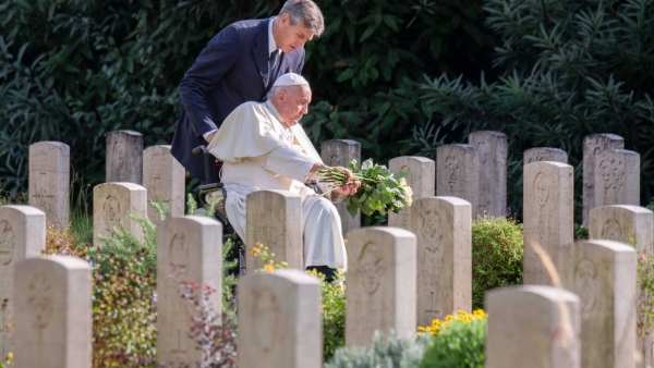Pope Francis leaves a bouquet of white roses at a grave