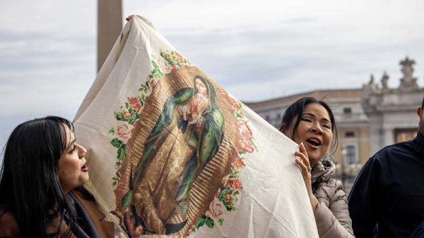 Women hold up an image of Our Lady of Guadalupe 