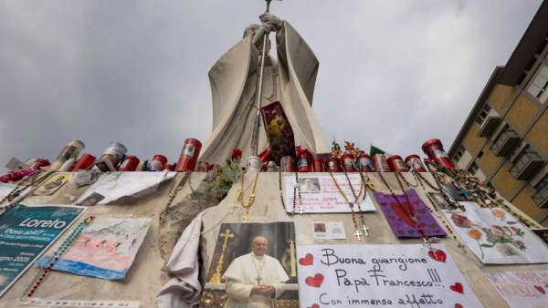 Drawings, votive candles, rosaries, flowers, cards for Pope Francis cover the base of a statue of St. John Paul II outside Rome's Gemelli hospital March 8, 2025. 