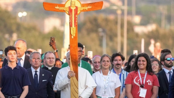 Pope Leo XIV carries the Jubilee Cross as he walks to the altar before the start of a prayer vigil with young people gathered in Tor Vergata in Rome Aug. 2