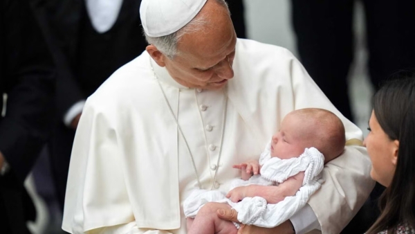 Pope Leo XIV holds a baby as he greets people in the Paul VI Audience Hall at the conclusion of his weekly general audience at the Vatican Aug. 20, 2025.