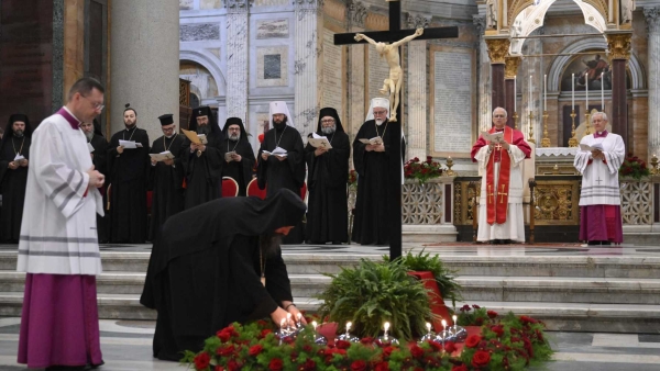 An Orthodox cleric places an oil lamp at the foot of a crucifix as Pope Leo XIV and other Orthodox leaders look on