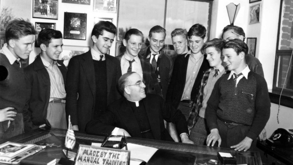 Father Edward Flanagan is surrounded by young men in his office at Boys Town in Omaha
